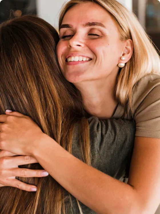 Pacientes mulheres se abraçando após uma sessão de terapia com a psicóloga Stela.